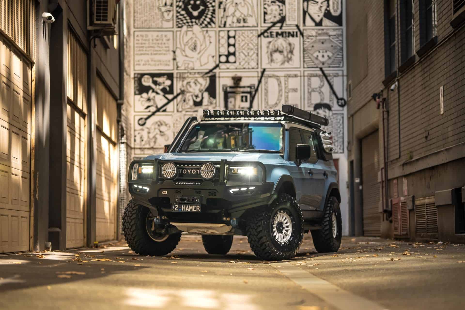 Black Toyota Landcruiser Prado with off-road accessories in an urban alleyway.
