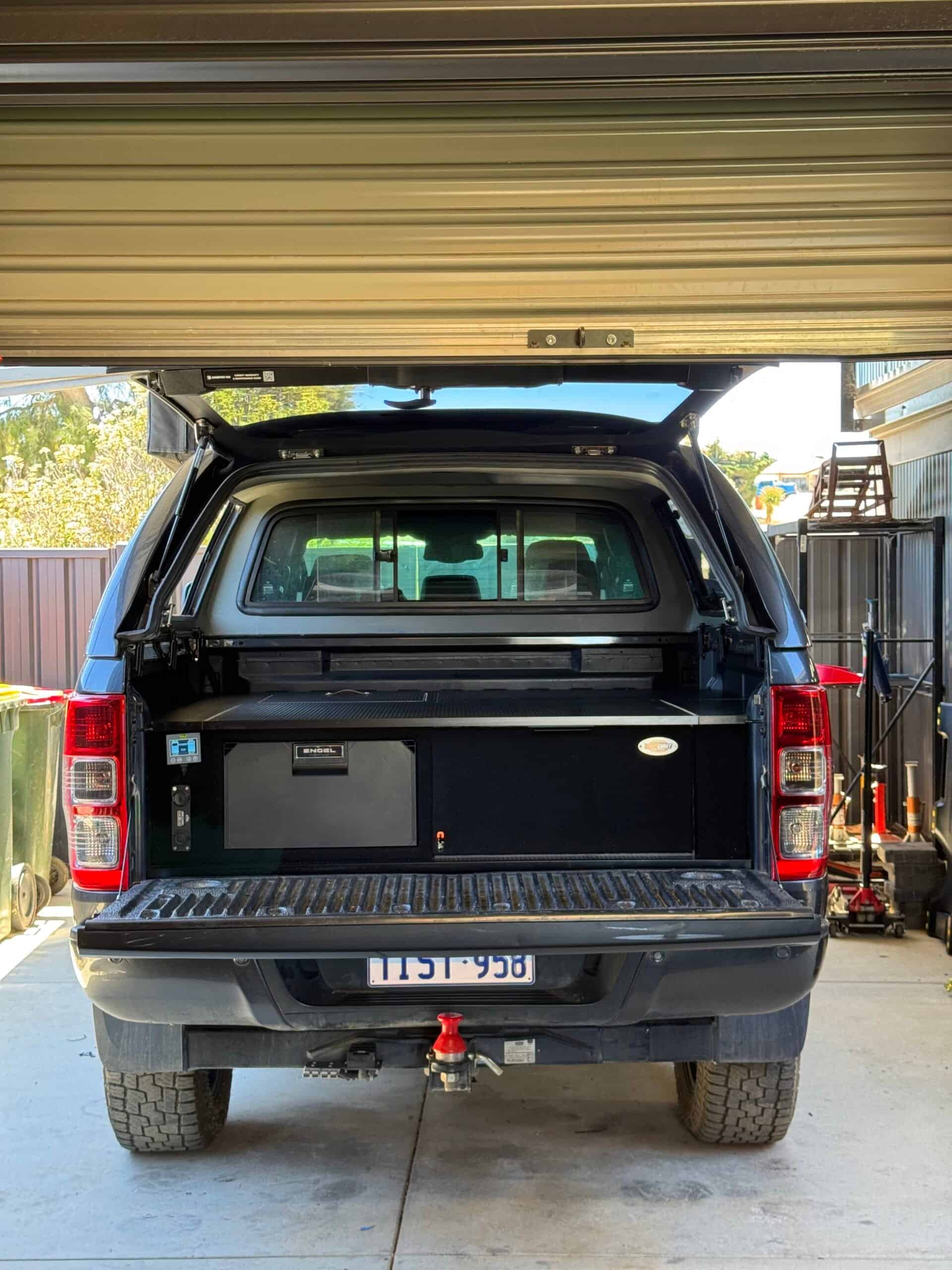 Black off-road vehicle with open rear door and storage setup in garage.